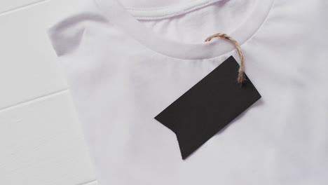 Video-of-flat-lay-of-white-t-shirt-with-tag-and-copy-space-on-white-background