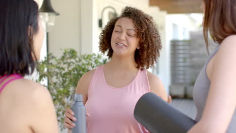 holding yoga mat and water bottle, woman smiling and talking with friends