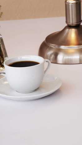computadora, diario, bolígrafos, taza de té y lámpara de mesa en la mesa