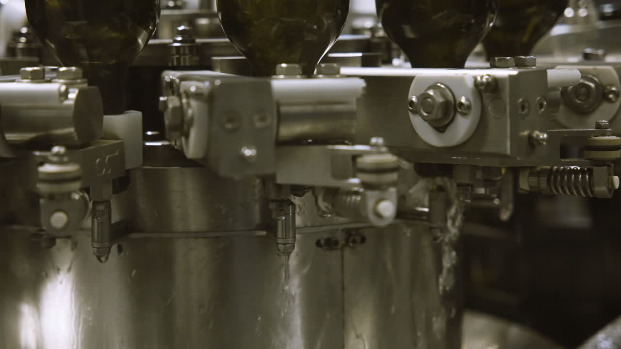 Close up of water rinsing out of empty wine bottles in bottling facility