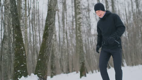 A-young-man-on-a-morning-jog-in-the-winter-forest-was-tired-and-stopped-to-rest-and-ran-on.-He-recovered-his-strength-and-overcame-fatigue-and-continued-to-run.-Perseverance-and-overcoming-weakness.-Striving-forward.-Slow-motion.-Healthy-lifestyle