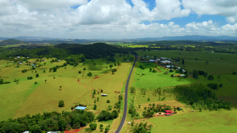 green landscape with a country road in the field in atherton tablelands, queensland, australia - aerial drone shot