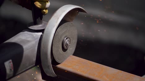 primer plano de un cortador de una viga metálica. trabajador masculino con máquina de molienda angular está cortando el metal