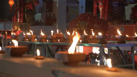 countless traditional and holy candles burning infront of buddhist temple with monks at night time during loy krathong festival in chiang mai, thailand