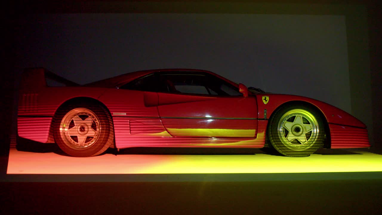A studio shot of the iconic red Ferrari F40, side view, captured on a tripod. Vibrant sunrise-like lightstreaks move from top to bottom, creating a dynamic visual effect.