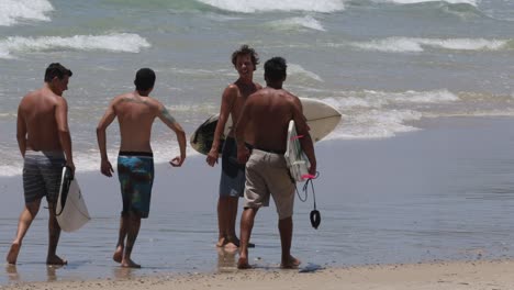 group of surfers carrying boards on a sunny beach