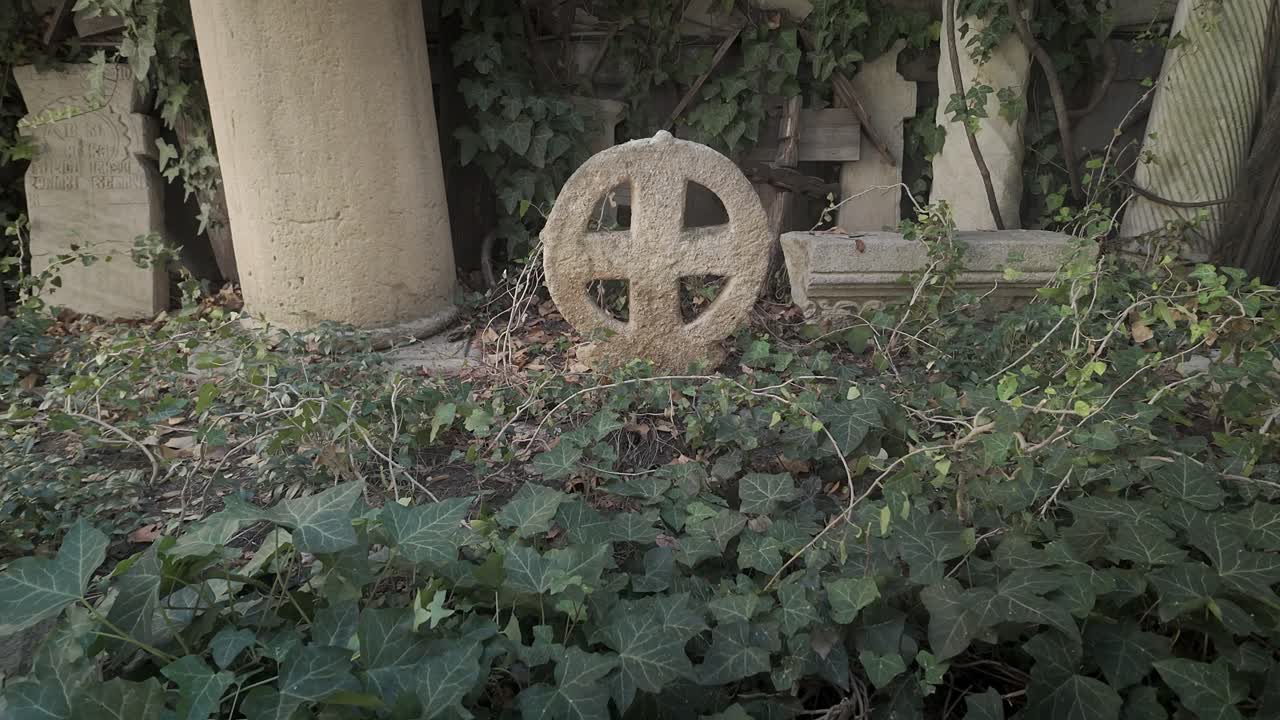 Round stone cross grave marker in Churchyard cemetery undergrowth