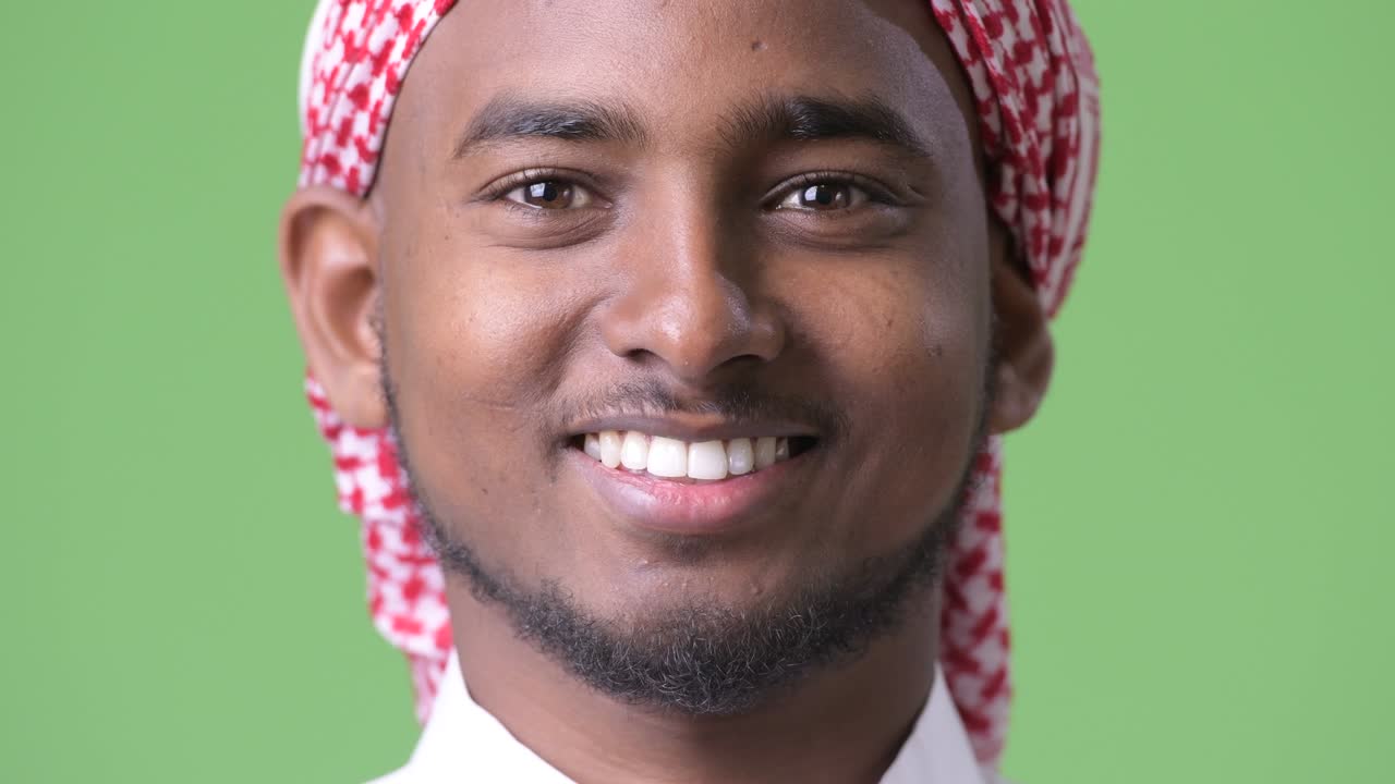 joven hombre africano guapo con ropa tradicional musulmana contra un fondo verde
