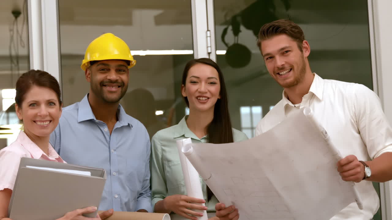 Equipo de arquitectos revisando planos y sonriendo a la cámara