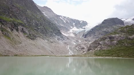 Seitlicher-Drohnenflug-See-Und-Steingletscher-Mit-Mann-Auf-Luftmatratze-In-Den-Urner-Alpen-In-Der-Schweiz