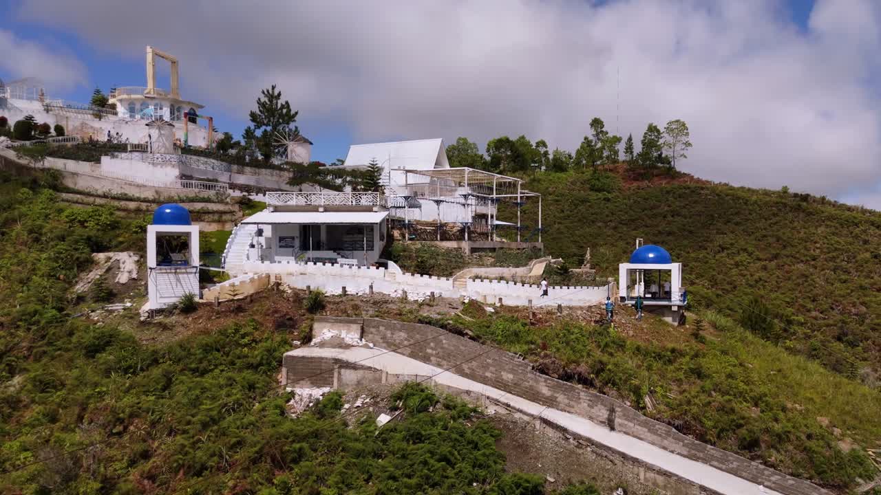 Aerial drone shot of a skybike attraction crossing lush green mountains in the Philippines, showing elevated adventure, tropical landscape, and scenic hills under bright daylight
