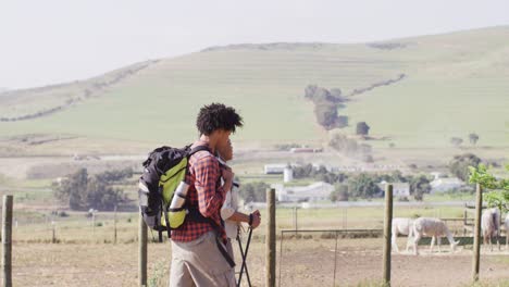 happy african american couple with backpacks, hiking with trekking poles together, slow motion