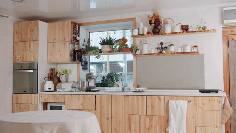 beautiful modern kitchen interior with wooden cabinets, indoor plants, oven, blender, and stylish decor items on floating shelves near large window