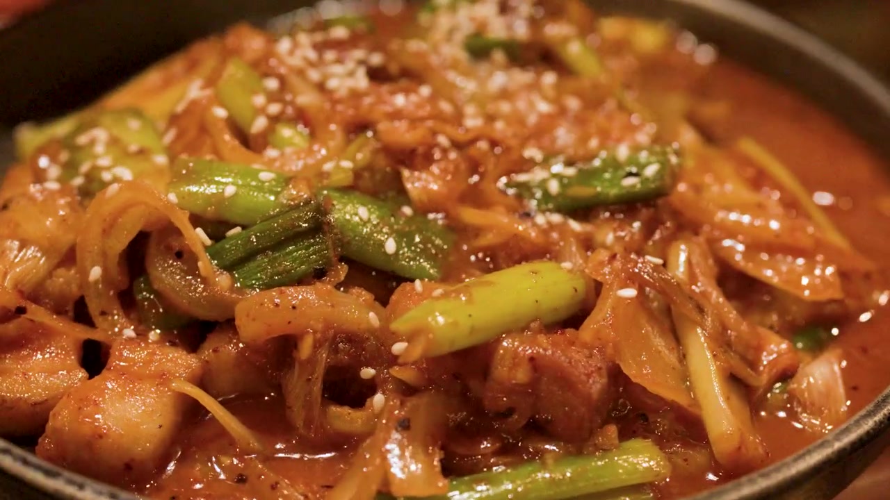 ภาพระยะใกล้ของหมูผัดเผ็ดเสิร์ฟในชามสีดำที่ร้านอาหาร