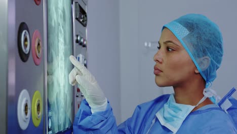 Close-up-of-African-American-female-doctor-looking-at-x-ray-report-on-light-box-in-hospital