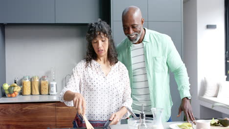 Feliz-Pareja-Birracial-Preparando-Huevos-Para-El-Desayuno-En-La-Cocina,-Cámara-Lenta