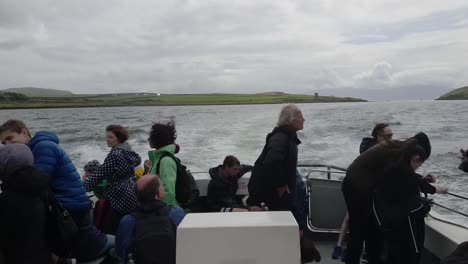 people, some movement on a small boat travelling out of the harbour in ireland.