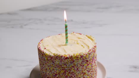 Studio-Shot-Birthday-Cake-Covered-With-Decorations-And-Single-Lit-Candle-1