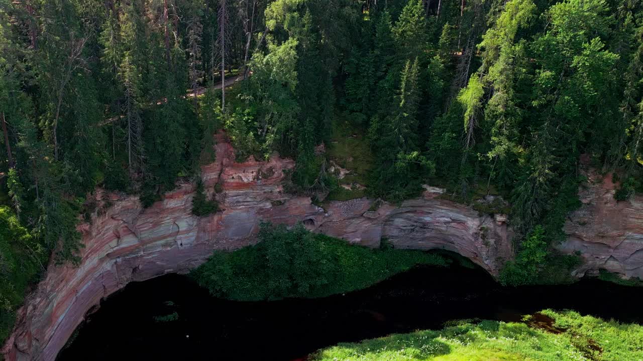 Taevaskoja in Estonia features steep sandstone cliffs a winding river and lush forest captured beautifully from above in a drone video highlighting the region’s untouched natural beauty