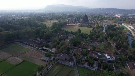 vista aérea de un grupo de ciclistas que pasan por el borde del templo de prambanan, que es un cadi con patrones religiosos hindúes