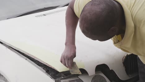 hombre africano pintando un coche