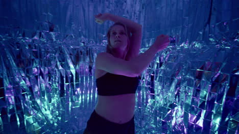 female dancer performing energetic movements in colorful neon lighting