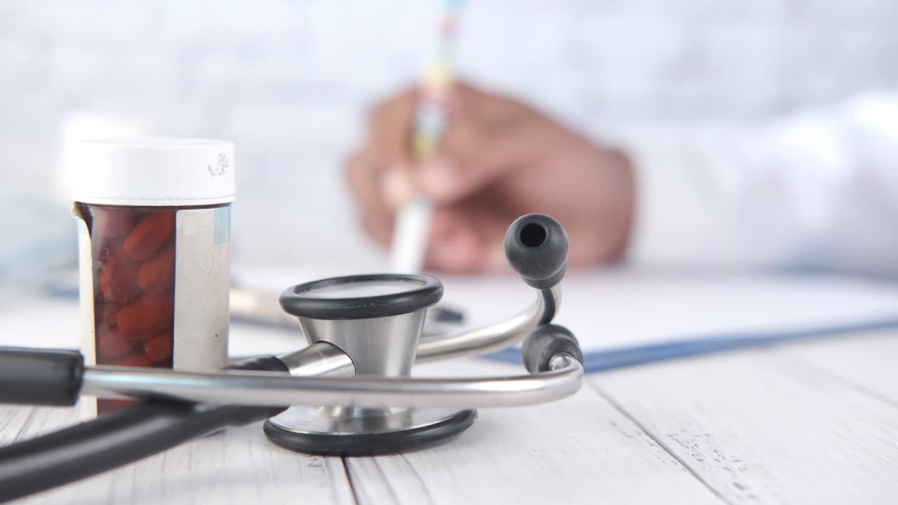 Mesa de consultório médico com estetoscópio, pílulas e prontuários médicos