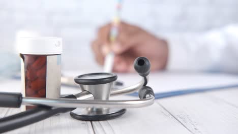 escritorio del consultorio del médico con estetoscopio, pastillas y registros médicos