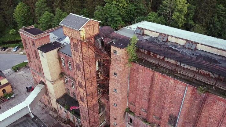 Imágenes aéreas de un dron sobrevolando un gran edificio de ladrillo de una antigua fábrica socialista abandonada en el centro de Alemania