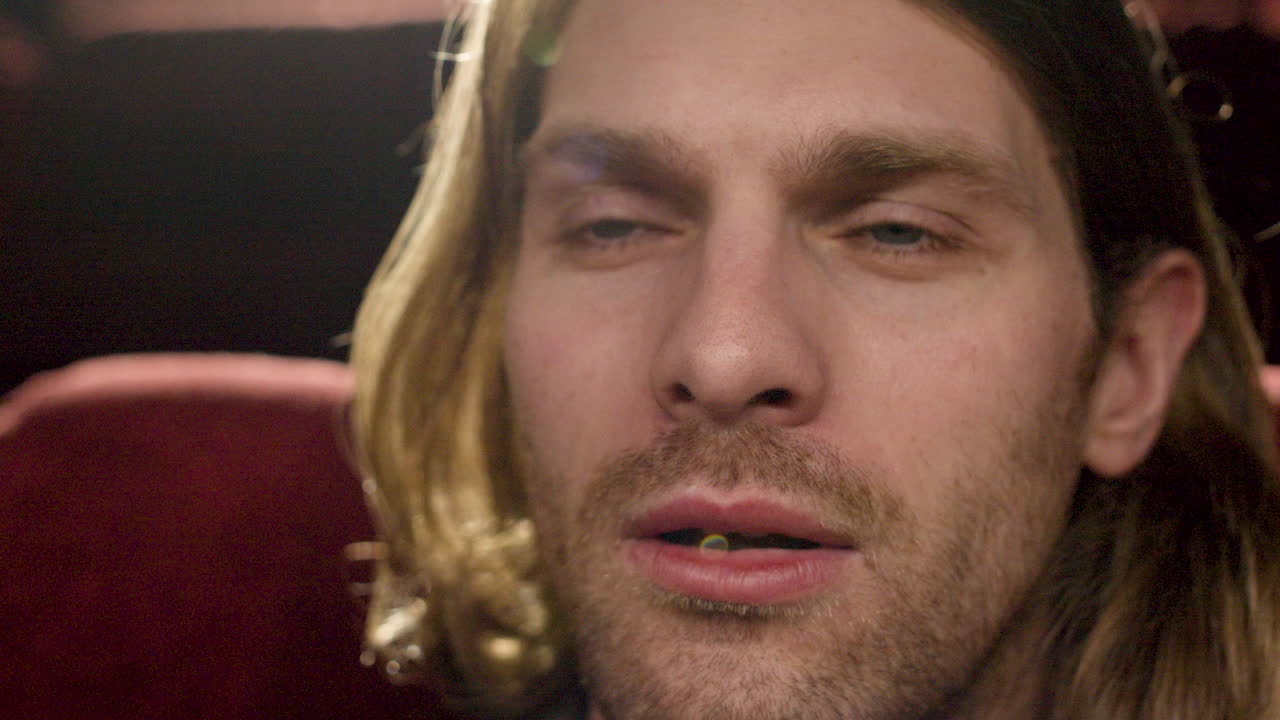 vista de cerca del hombre rubio viendo una película y sonriendo en el cine