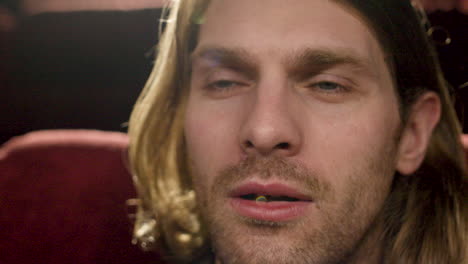 close up view of blond man watching a movie and smiling in the cinema