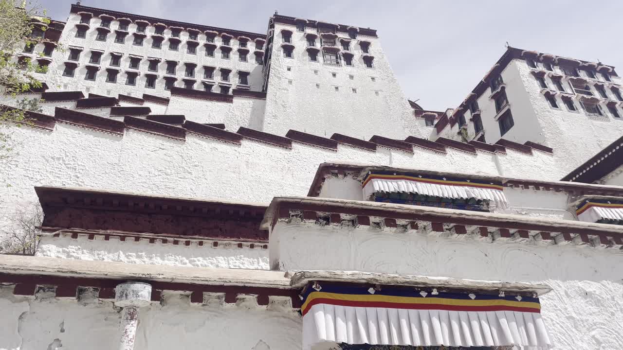 Establishing upward angle of Potala Palace in Lhasa with mountain backdrop under cloudy sky
