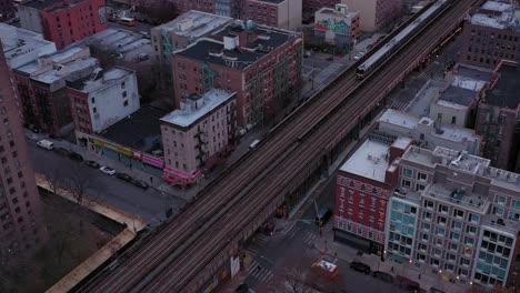 stationary aerial shot of elevated train tracks running through harlem new york city, two school bus cross under viaduct