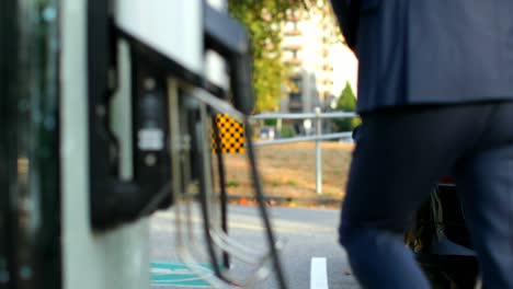 Businessman-charging-electric-car-at-charging-station-4k