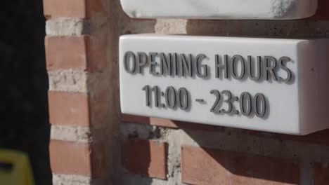 opening hours sign on a brick wall