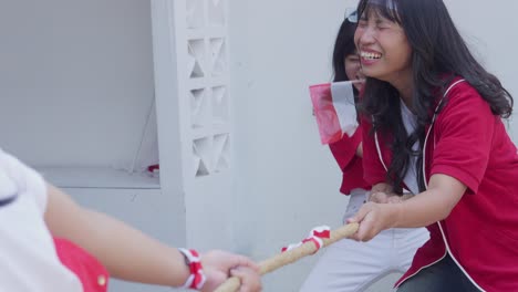 asian young people playing tug of war games to celebrate indonesian independence day