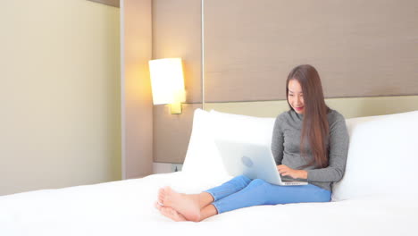 연봉 보너스에 대한 이메일을 노트북에 받았을 때 아시아 여성이 승리의 표정으로 손을 들어 올립니다.