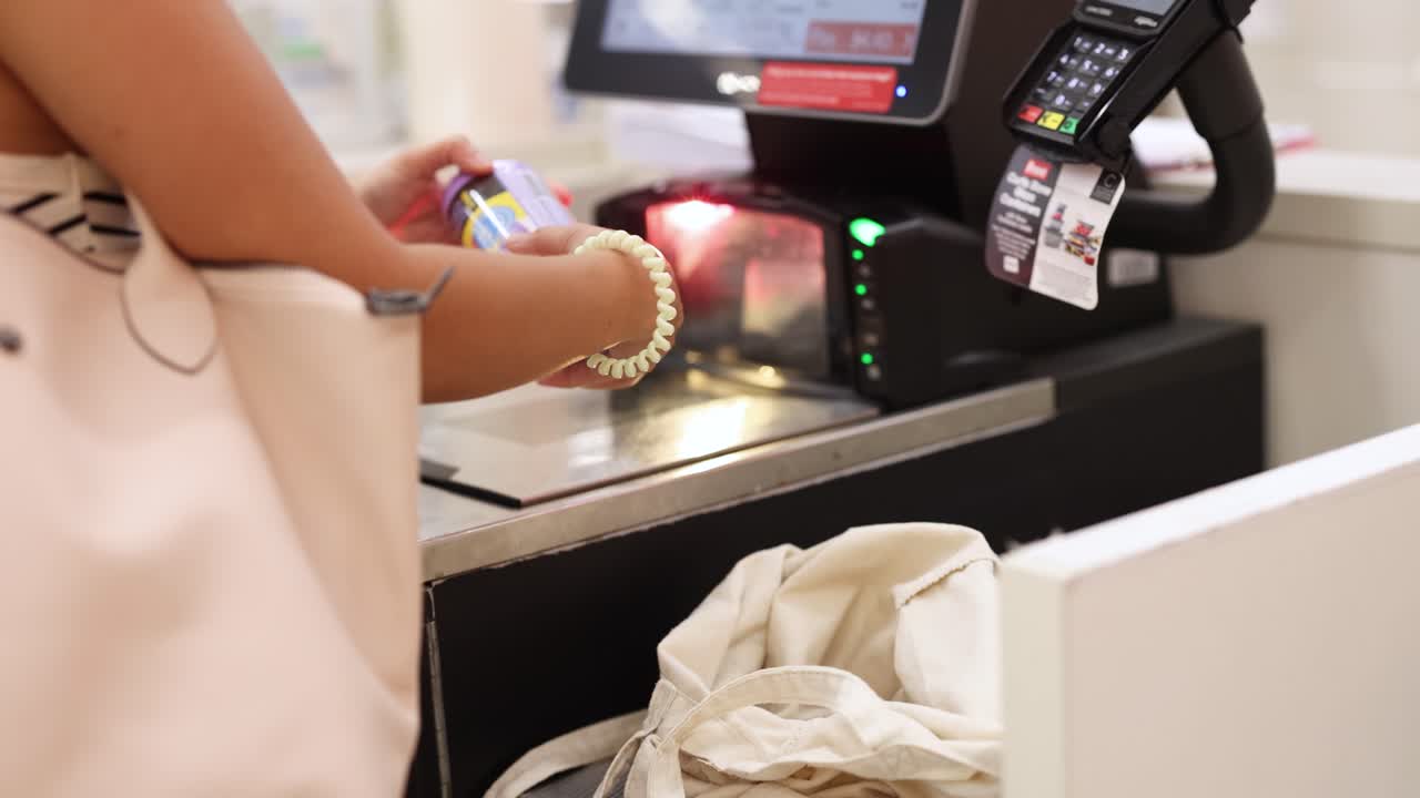A customer uses a self-checkout machine for cashless payment in a well-lit retail environment