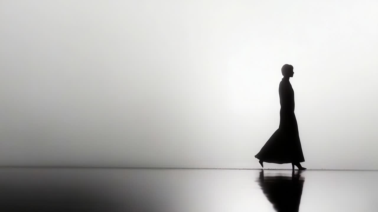 A captivating silhouette of a model gracefully walking across a reflective surface, showcasing elegance and artistry in fashion against a stark, minimalistic background
