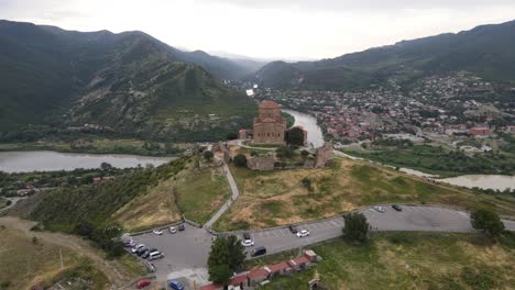 Aerial-shot-of-Jvari-church-Mtskheta-Georgia-river-city-mountains-meadows-forest