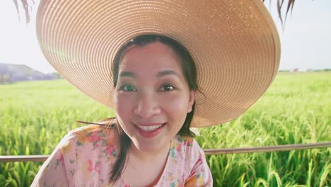 Beautiful-young-Asian-woman-with-hat-in-rice-field-making-video-call