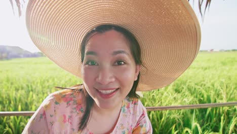 beautiful young asian woman with hat in rice field making video call