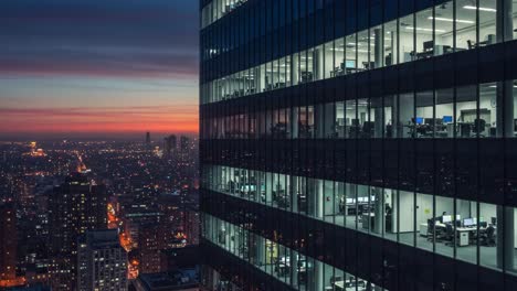 a stunning evening view from a high-rise office building, showcasing city lights and office interiors against the backdrop of a colorful sunset sky