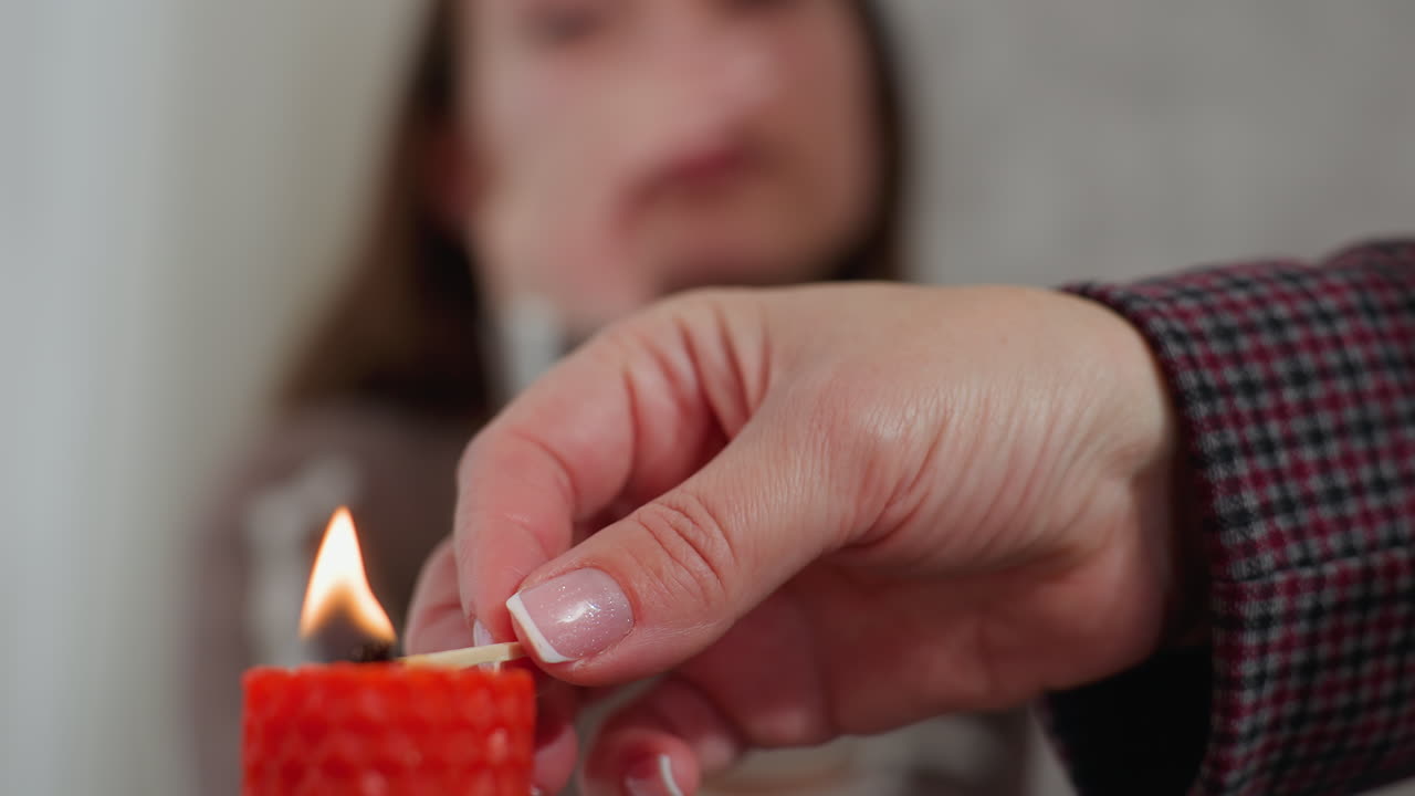 손으로 은 불을 켜고 있는 은 사람이 배경에서 지켜보는 동안, 불꽃의 따뜻한 빛은 부드러운 초점 관찰자와 대조된다.