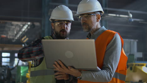 factory workers reviewing plans on laptop