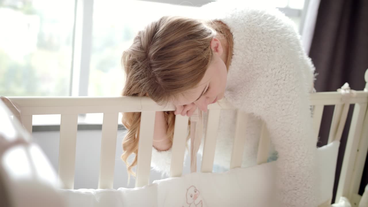 Madre felice vicino alla culla del bambino. Mamma che guarda il bambino che dorme nella culla.