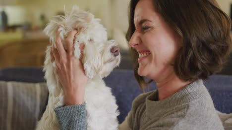 Mujer-Caucásica-Sonriente-Besando-Y-Abrazando-A-Su-Perro-Sentado-En-El-Sofá-De-Casa