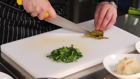 chef chopping pickles and parsley