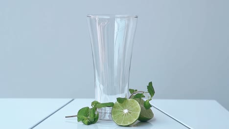 Leeres-Hohes-Glas-Steht-Auf-Weißer-Oberfläche-In-Der-Nähe-Von-Limettenhälften