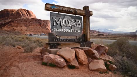 welcome to moab utah sign on a cloudy day with vehicles driving on highway 191, static